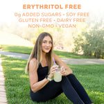 Woman in black activewear sitting on grass holding a jar with a straw outdoors in daylight
